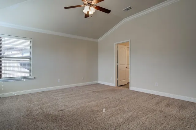 an empty room with a chandelier fan and windows