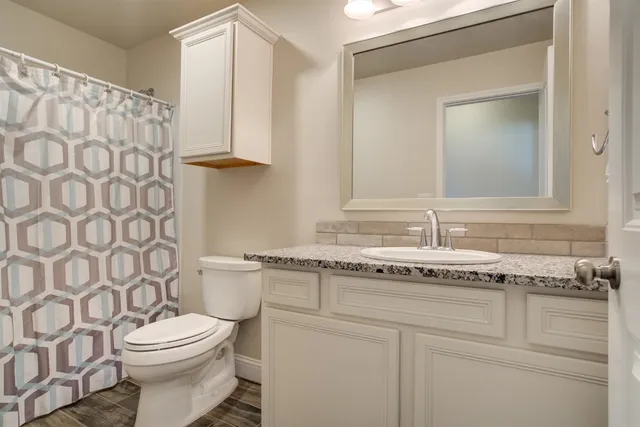 a bathroom with a granite countertop sink a toilet and a mirror