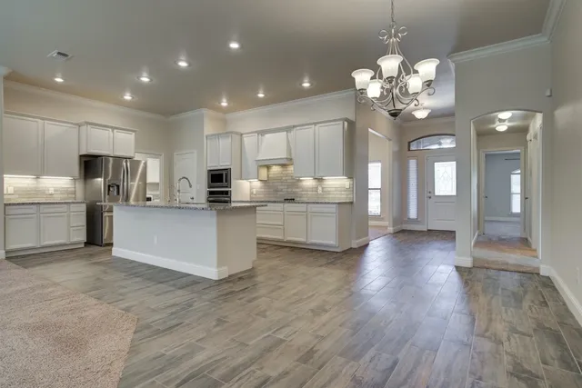 a large white kitchen with a refrigerator a stove a microwave oven a dining table and chairs