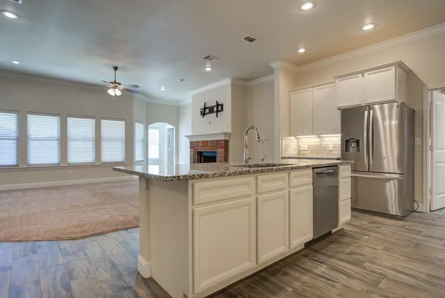 a kitchen with stainless steel appliances granite countertop a refrigerator a sink dishwasher a stove and a refrigerator with wooden floor