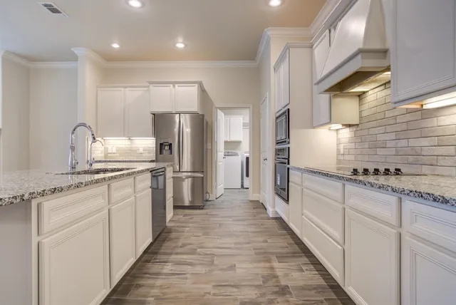 a large kitchen with kitchen island granite countertop a sink and stainless steel appliances