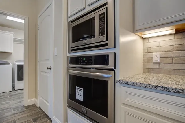 a kitchen with granite countertop white cabinets and stainless steel appliances