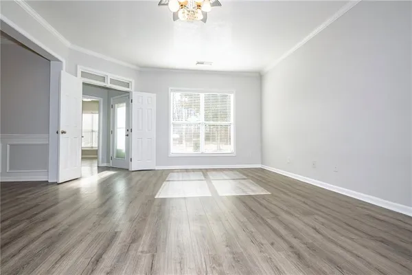a view of an empty room with wooden floor and a window