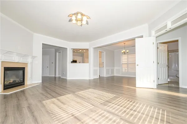 a view of an empty room with wooden floor fireplace and a window