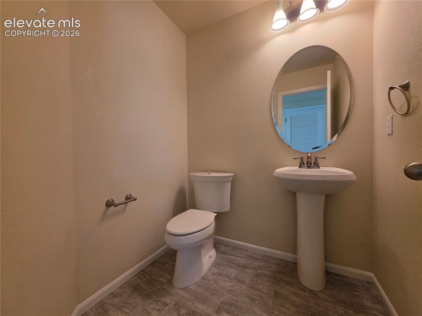 874 Diamond Rim Drive Colorado Springs, CO 80921 - Photo 4 of 28 Pedestal sink with chrome faucet, oval mirror, wall-mounted light fixture, and wood-look flooring
