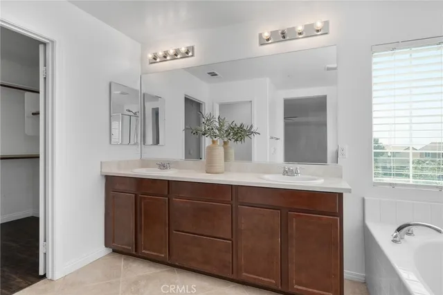 a spacious bathroom with a double vanity sink a large mirror and a bathtub