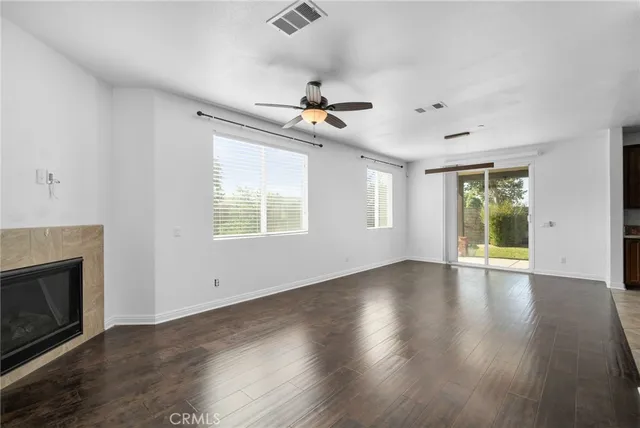 an empty room with wooden floor fireplace and windows