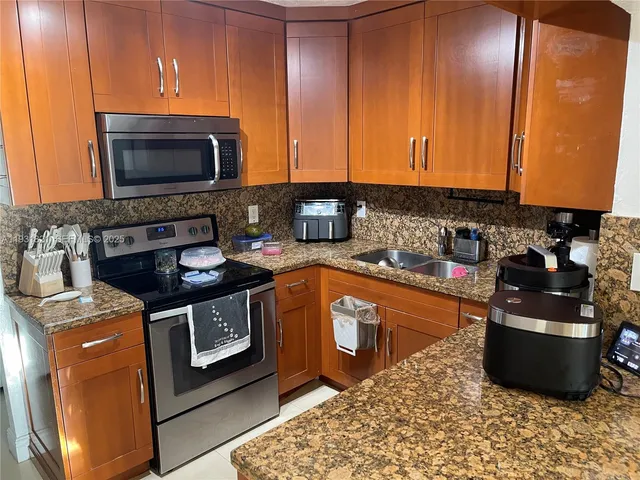 a kitchen with stainless steel appliances granite countertop a stove a sink and a microwave