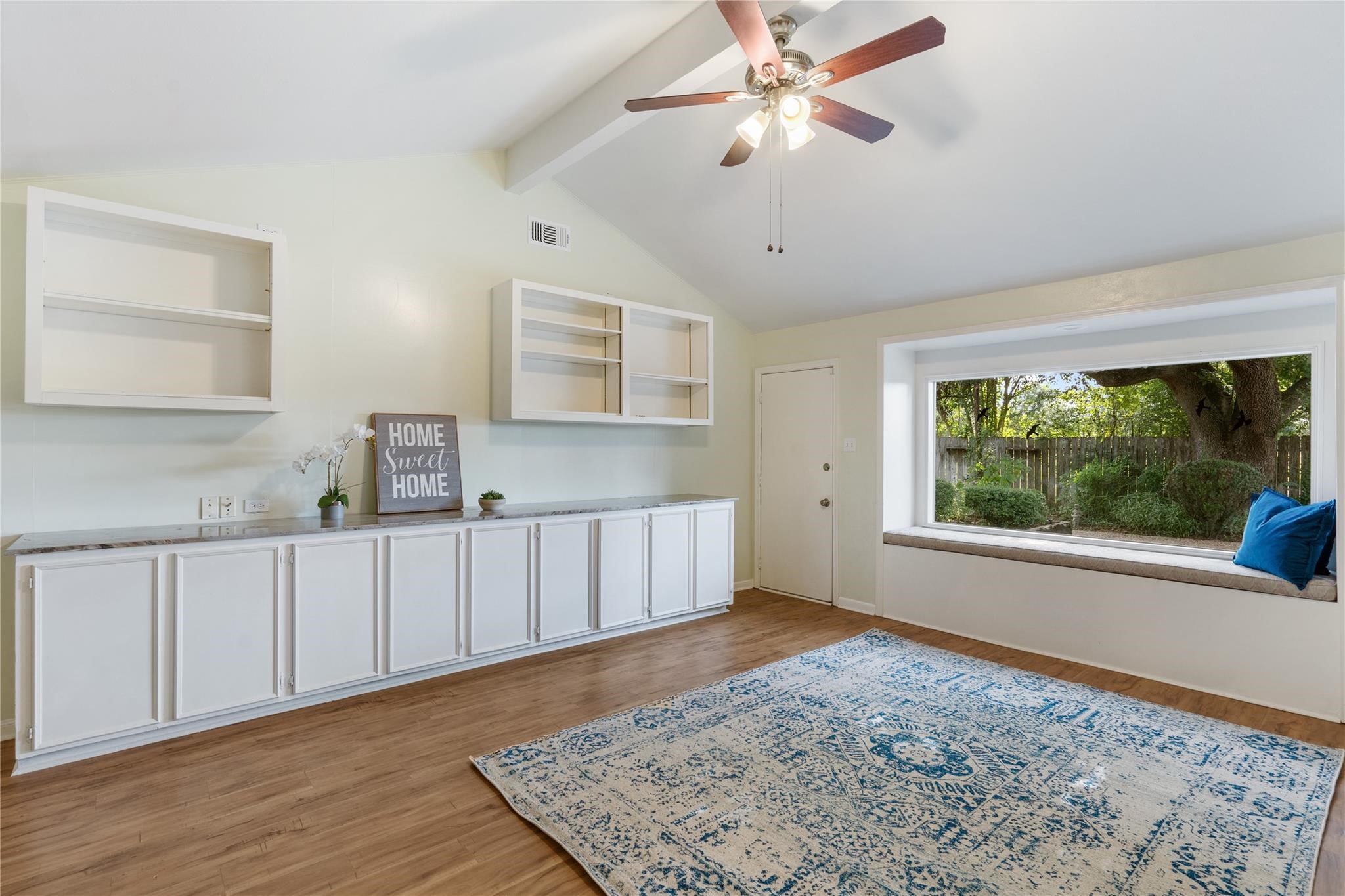 a view of an empty room with a window and wooden floor