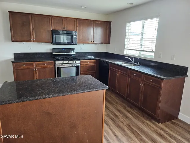 a kitchen with stainless steel appliances granite countertop a sink stove and microwave