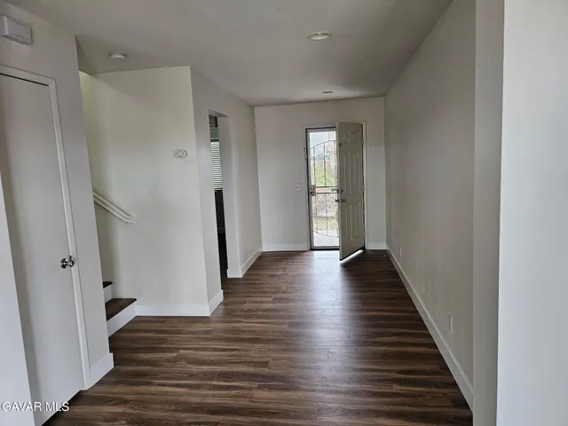 a view of a hallway with wooden floor and staircase