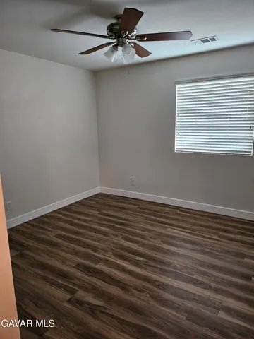 a view of a room with wooden floor and a ceiling fan