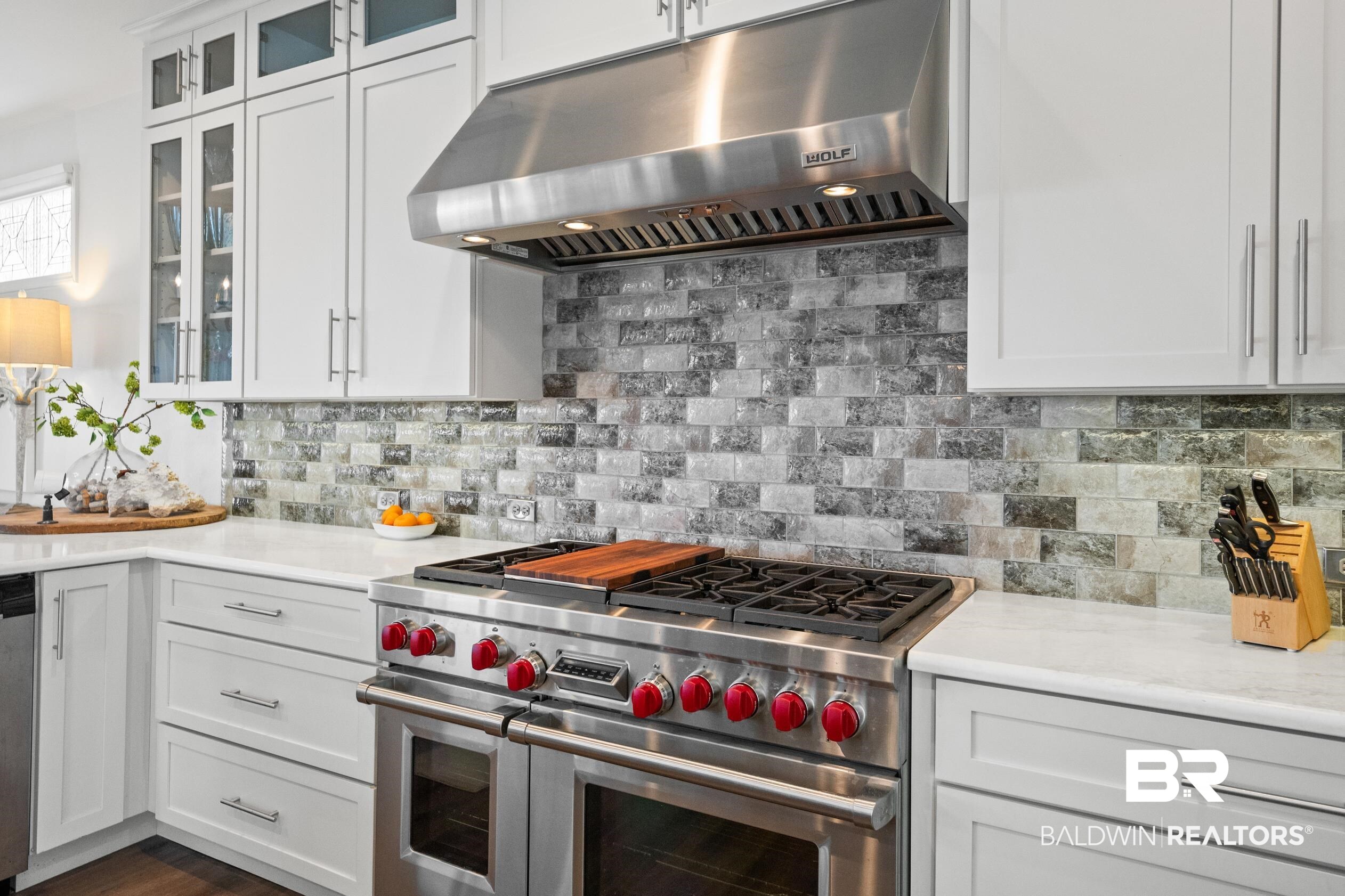 30954 River Road Orange Beach, AL 36561 - Photo 25 of 59 Kitchen with appliances with stainless steel finishes, range hood, light countertops, and white cabinetry