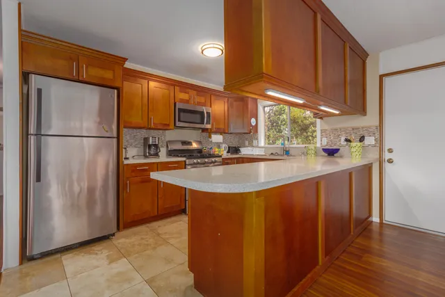 a kitchen with stainless steel appliances granite countertop a sink a stove a microwave oven cabinets and a window