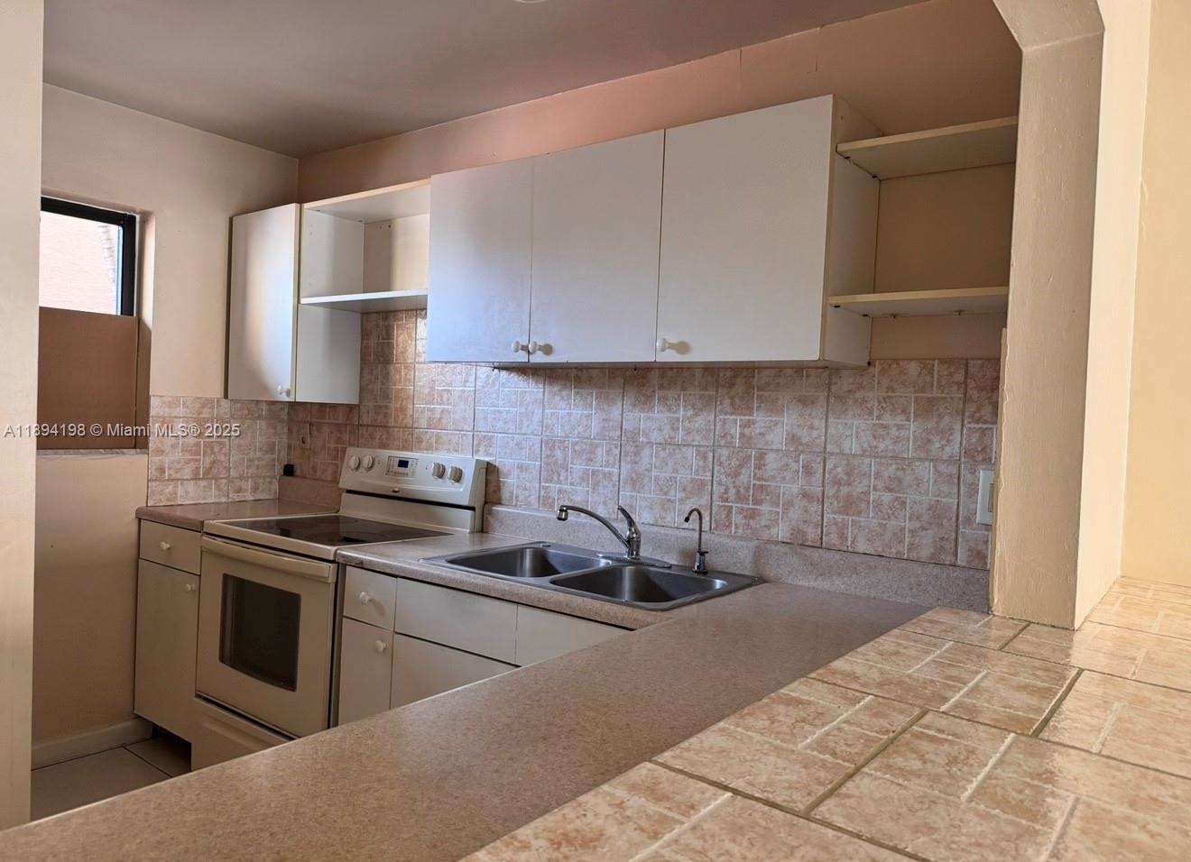 6055 West 19th Avenue, Unit 304 Hialeah, FL 33012 - Photo 2 of 24 a kitchen with a sink stove and refrigerator