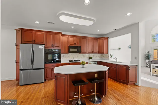 a kitchen with stainless steel appliances granite countertop a refrigerator a sink dishwasher a stove with wooden cabinets and wooden floor