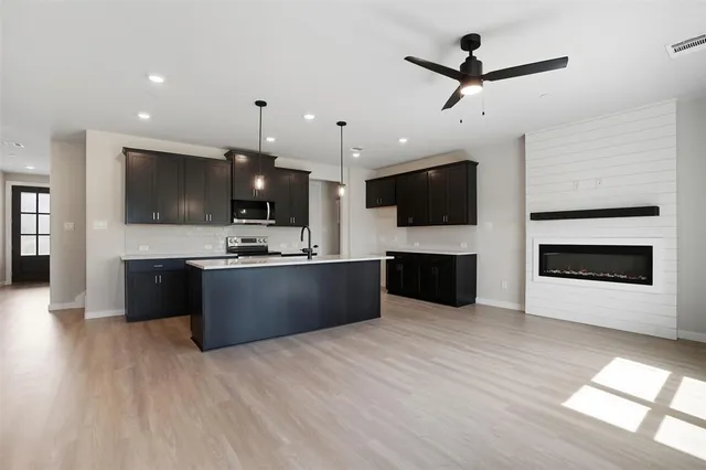 a large kitchen with stainless steel appliances a large counter top a stove a sink and a fireplace