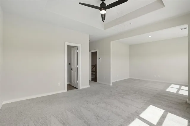 an empty room with a ceiling fan and carpet