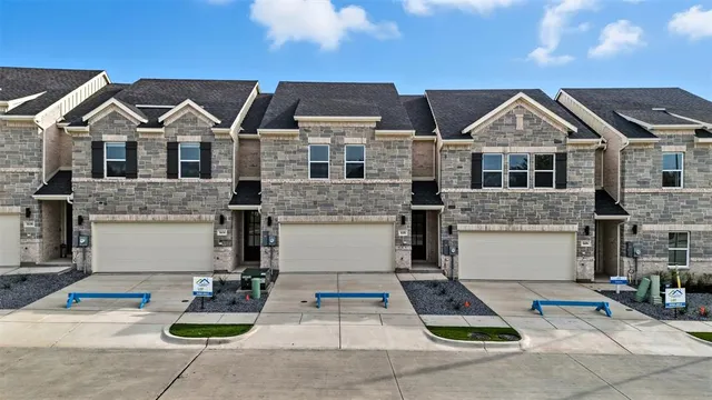 a view of a white house with large windows and plants