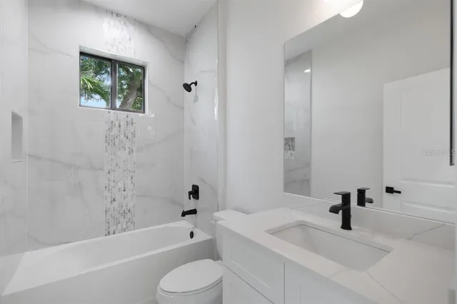 a bathroom with a bathtub shower sink vanity and toilet