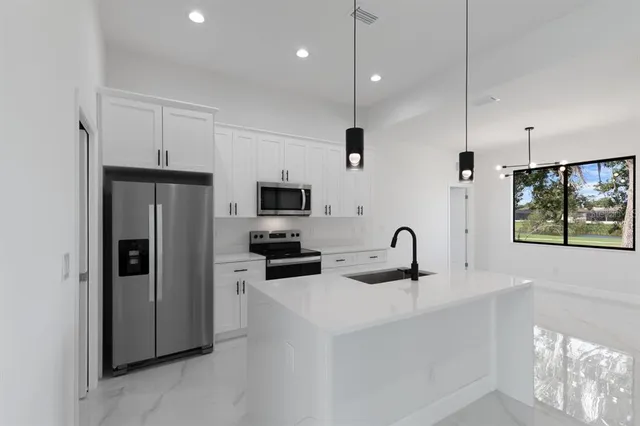 a kitchen with stainless steel appliances a refrigerator a sink a stove a microwave and island