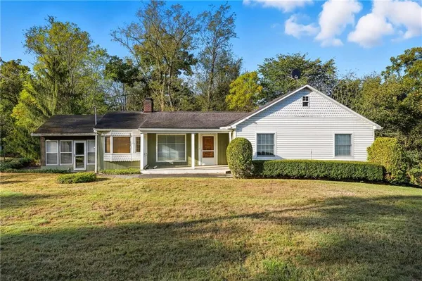 a front view of house with yard and trees in the background