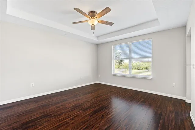 an empty room with wooden floor and ceiling fan