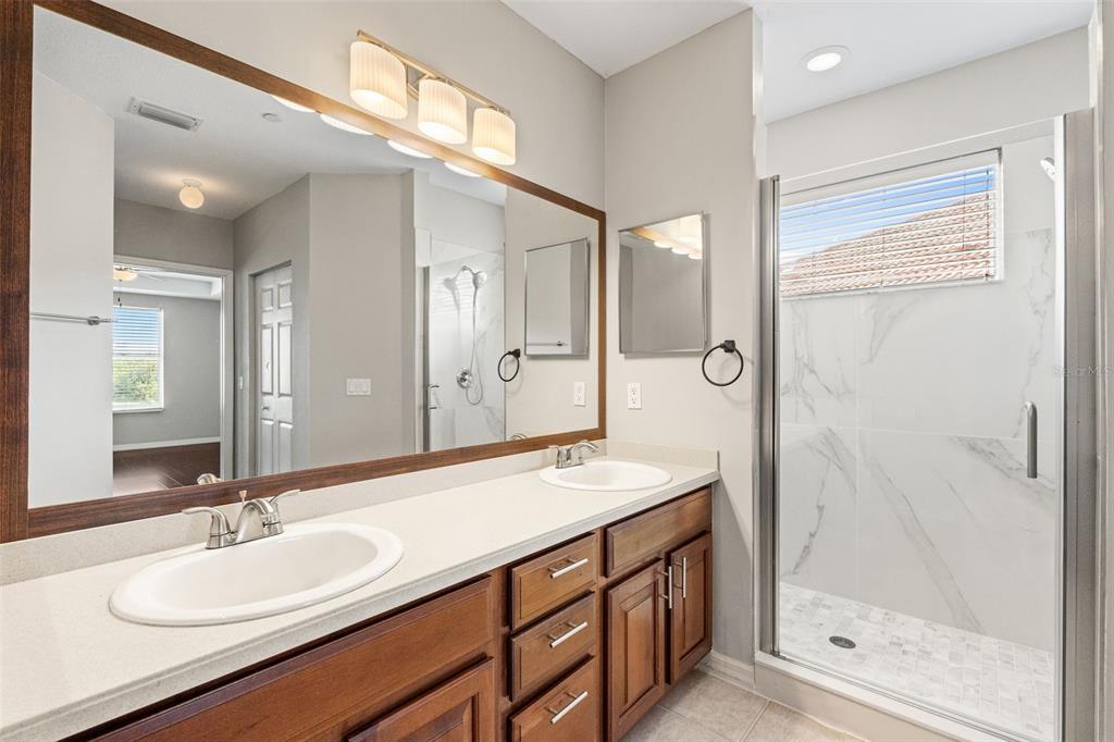 7187 Boca Grove Place, Unit 201 Lakewood Ranch, FL 34202 - Photo 20 of 48 a bathroom with a double vanity sink mirror and shower