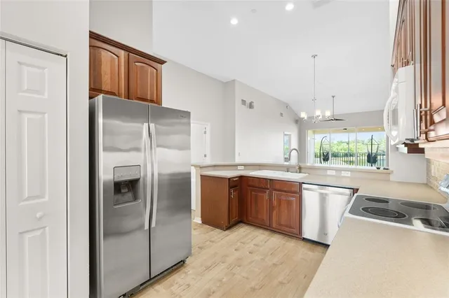 a kitchen with stainless steel appliances granite countertop a refrigerator a sink dishwasher a stove with white cabinets and wooden floor