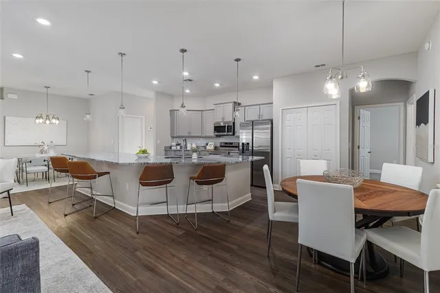 a kitchen with stainless steel appliances granite countertop a sink a stove top oven a refrigerator cabinets and wooden floor