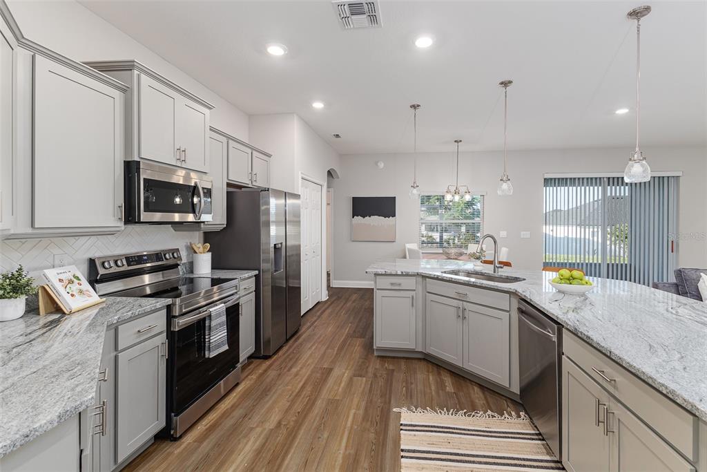 3150 Kendal Way Lakeland, FL 33813 - Photo 14 of 61 a kitchen with stainless steel appliances granite countertop a sink a stove top oven a refrigerator cabinets and wooden floor