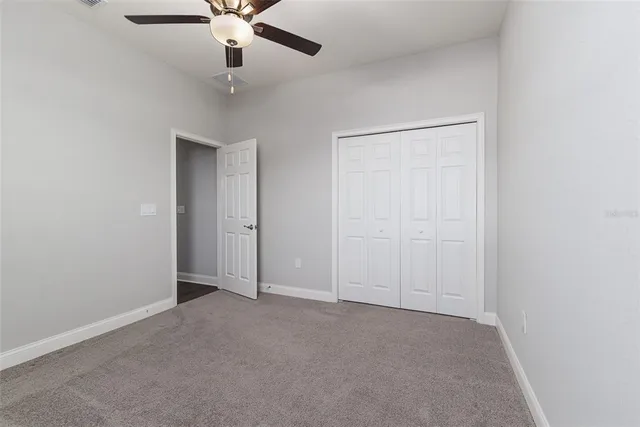 an empty room with a ceiling fan and carpet