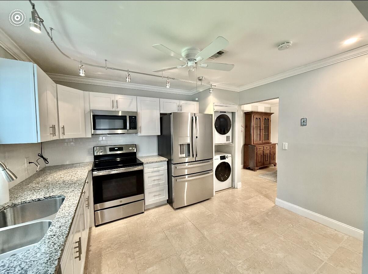 828 Timberview Drive, Unit D Fort Pierce, FL 34982 - Photo 5 of 28 a kitchen with stainless steel appliances granite countertop a refrigerator oven a sink dishwasher and white cabinets with wooden floor