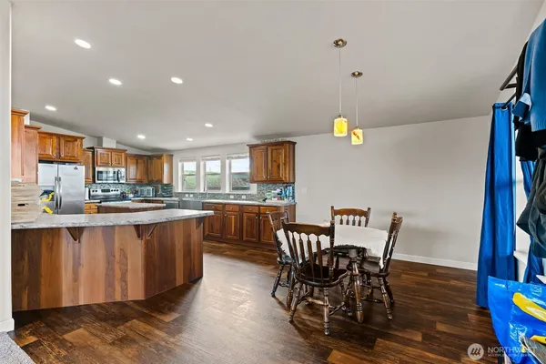 a kitchen with stainless steel appliances granite countertop a dining table chairs and granite counter tops