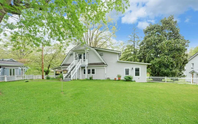 a view of house with a big yard and large trees