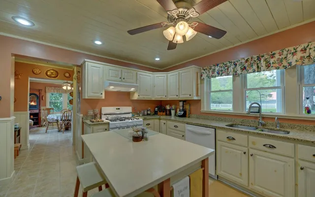 a kitchen with a stove a sink dishwasher a dining table and chairs with wooden floor
