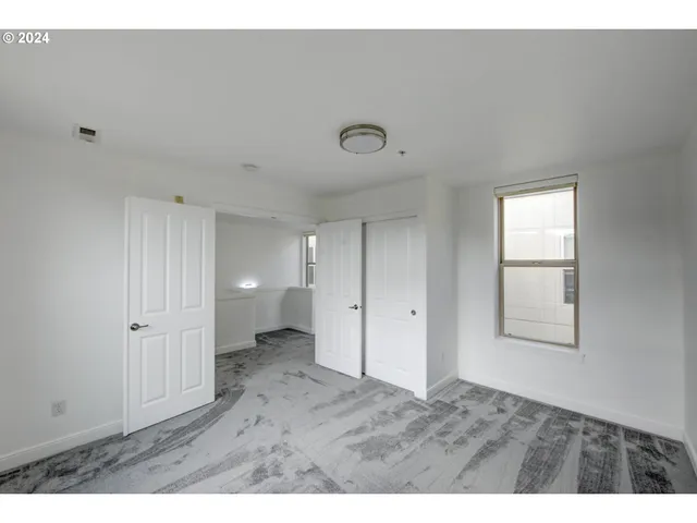 a view of an empty room with closet and a window