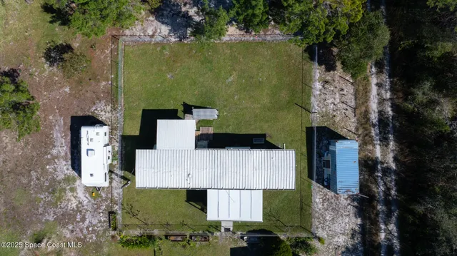 an aerial view of a house with a yard and large tree