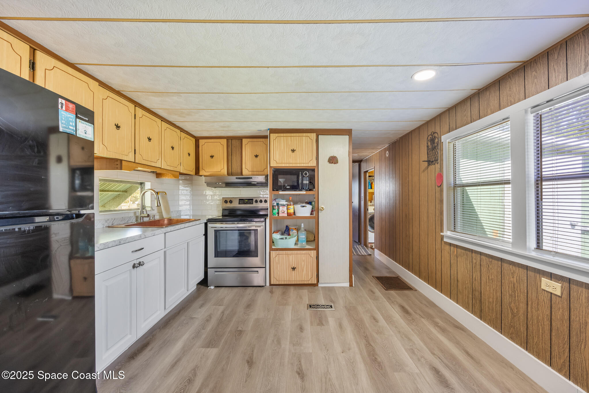 4895 Orange Street Mims, FL 32754 - Photo 7 of 33 a kitchen with stainless steel appliances a refrigerator a stove top oven a sink dishwasher and wooden cabinets