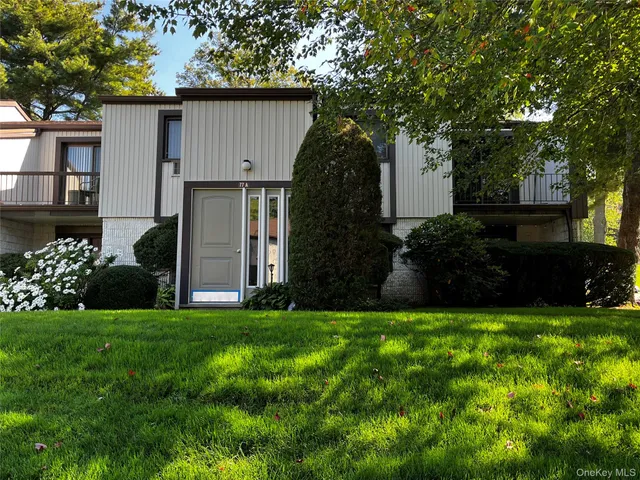 a view of a house with a yard and a large tree
