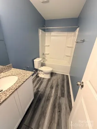 a spacious bathroom with a granite countertop sink a toilet and a tub