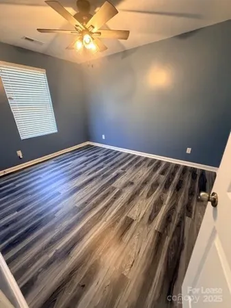 en empty room with wooden floor and fan