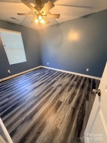 en empty room with wooden floor and fan