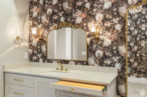 1141 East Lost Ridge Drive Washington, UT 84780 - Photo 70 of 108 Vanity space featuring floral wallpaper, an arched mirror with a gold-tone frame, and two wall-mounted sconces