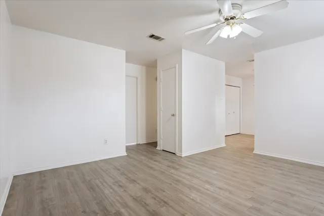 an empty room with wooden floor and ceiling fan