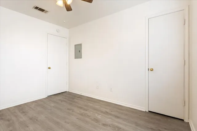 an empty room with a ceiling fan and wooden floor