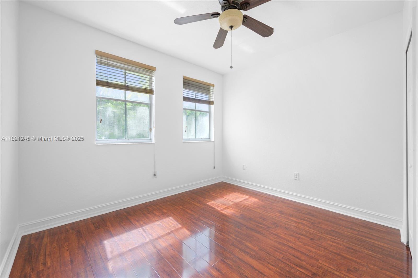 7633 Northwest 114th Path, Unit 7633 Doral, FL 33178 - Photo 14 of 25 an empty room with wooden floor fan and windows