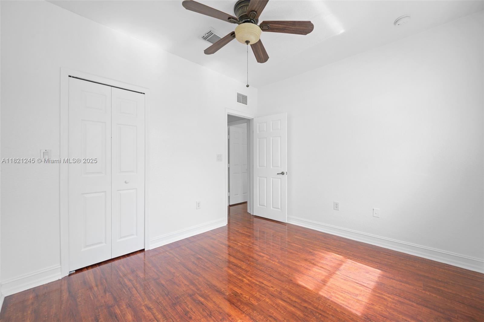 7633 Northwest 114th Path, Unit 7633 Doral, FL 33178 - Photo 15 of 25 a view of an empty room with wooden floor and a ceiling fan
