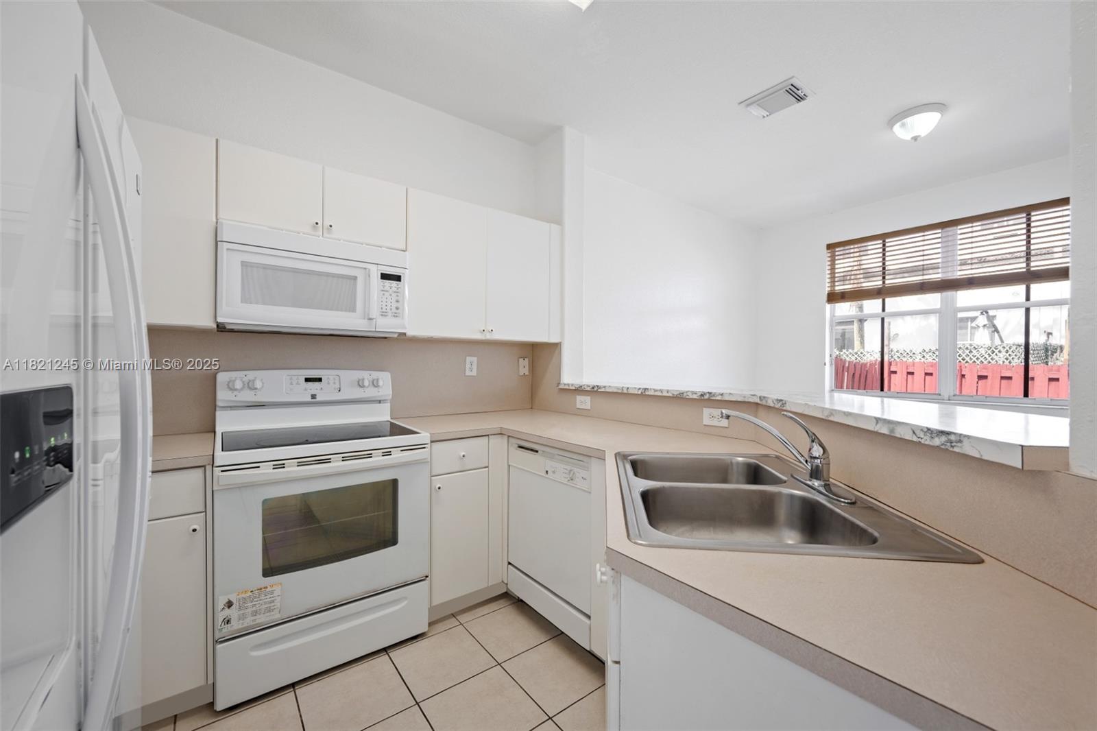 7633 Northwest 114th Path, Unit 7633 Doral, FL 33178 - Photo 5 of 25 a view of a kitchen that shows a sink and a stove top oven