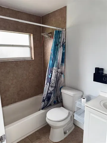 an empty room with chandelier fan and window